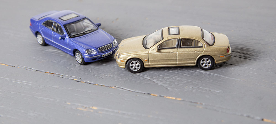 Verkehrsunfallregulierung. Darstellung eines Verkehrsunfalles mit zwei Modellautos auf einem Tisch.