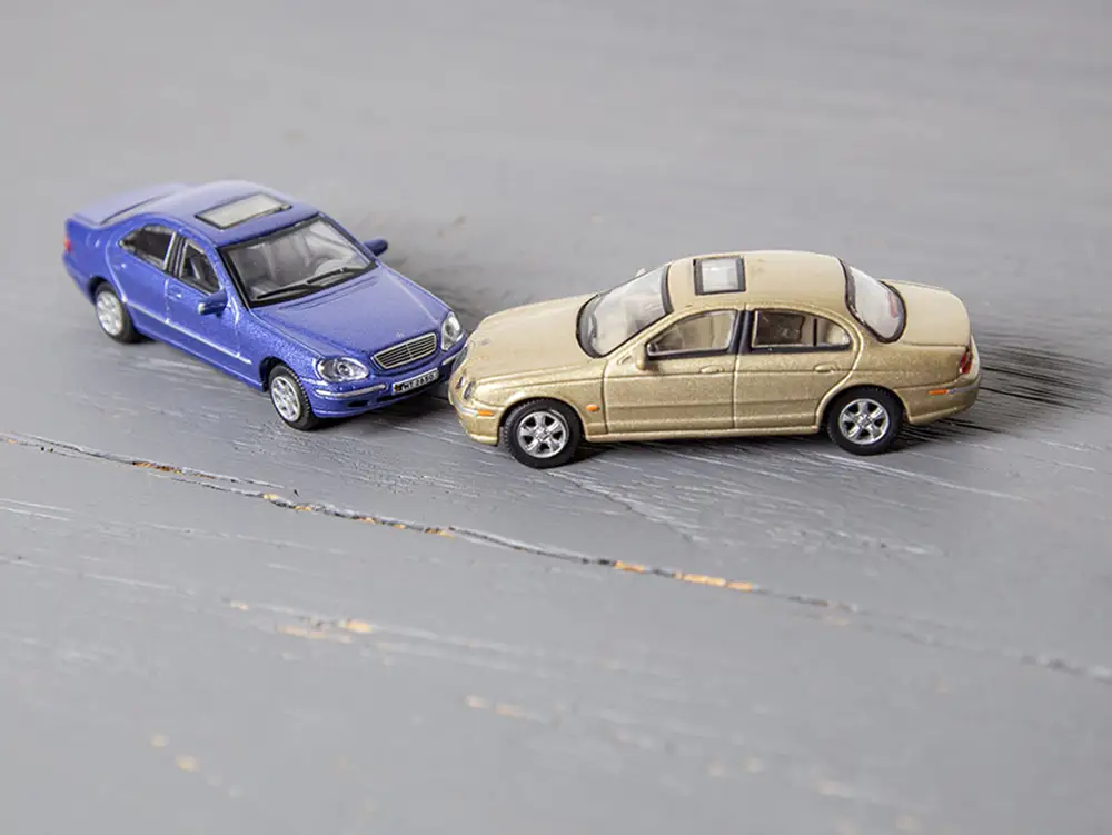 Zwei kollidierte Modellautos als Symbol für Unfallregulierung im Verkehrsrecht